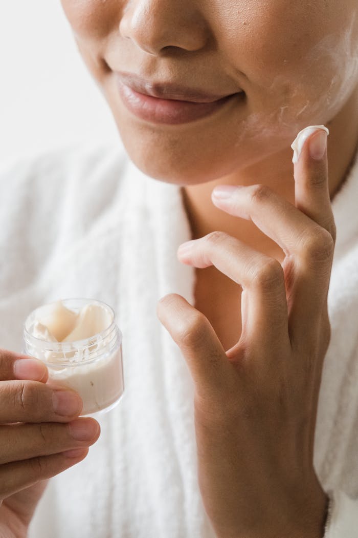Close-up of a woman applying moisturizing cream to her face as part of a skincare routine.